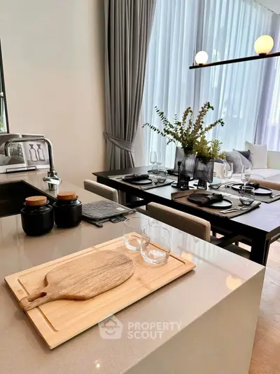 Modern open kitchen with dining area, featuring elegant decor and natural light.