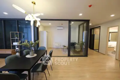 Spacious modern living room with dining area and glass partition, featuring elegant lighting and wooden flooring.