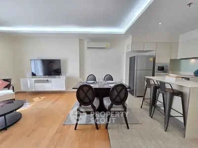 Spacious modern living room with dining area and open kitchen, featuring sleek furniture and natural light.