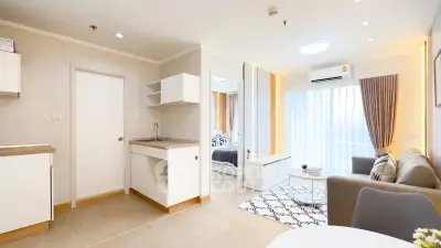 Modern open-plan living room with kitchen and bedroom view, featuring stylish decor and natural light.