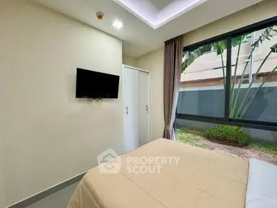 Modern bedroom with garden view, featuring a wall-mounted TV and large window for natural light.