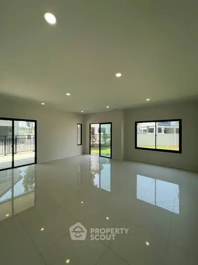 Spacious and bright empty living room with large windows and modern tile flooring.