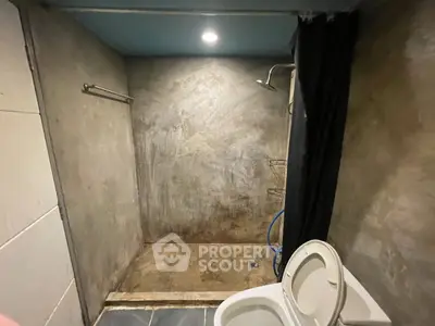 Modern industrial-style bathroom with concrete walls and open shower design.