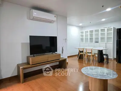 Modern living room with wooden flooring, TV setup, and dining area