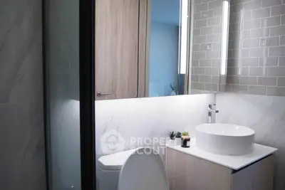 Modern bathroom with sleek design, featuring a round basin and stylish lighting.