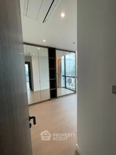 Spacious modern bedroom with mirrored closet doors and city view balcony access.