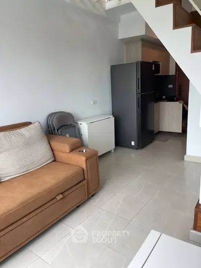 Modern living room with brown sofa and open kitchen layout in cozy apartment
