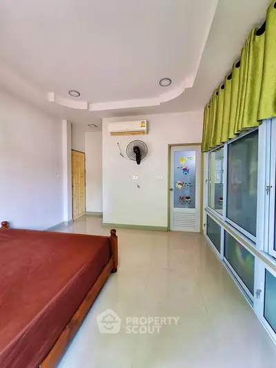 Spacious bedroom with air conditioning and large windows for natural light.