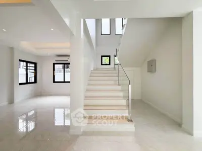 Spacious modern interior with elegant staircase and large windows, perfect for natural light lovers.