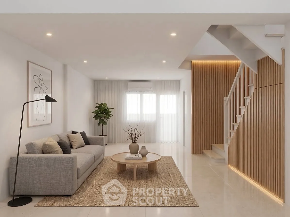 Modern living room with stylish decor and staircase, featuring a cozy gray sofa and elegant lighting.