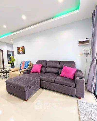 Modern living room with stylish gray sofa and vibrant pink cushions, perfect for relaxation and entertainment.