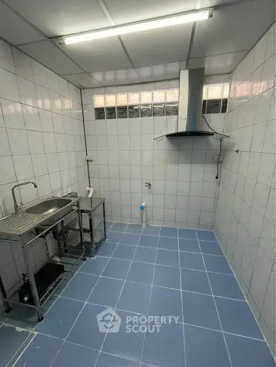 Spacious tiled kitchen with stainless steel sink and modern exhaust hood.