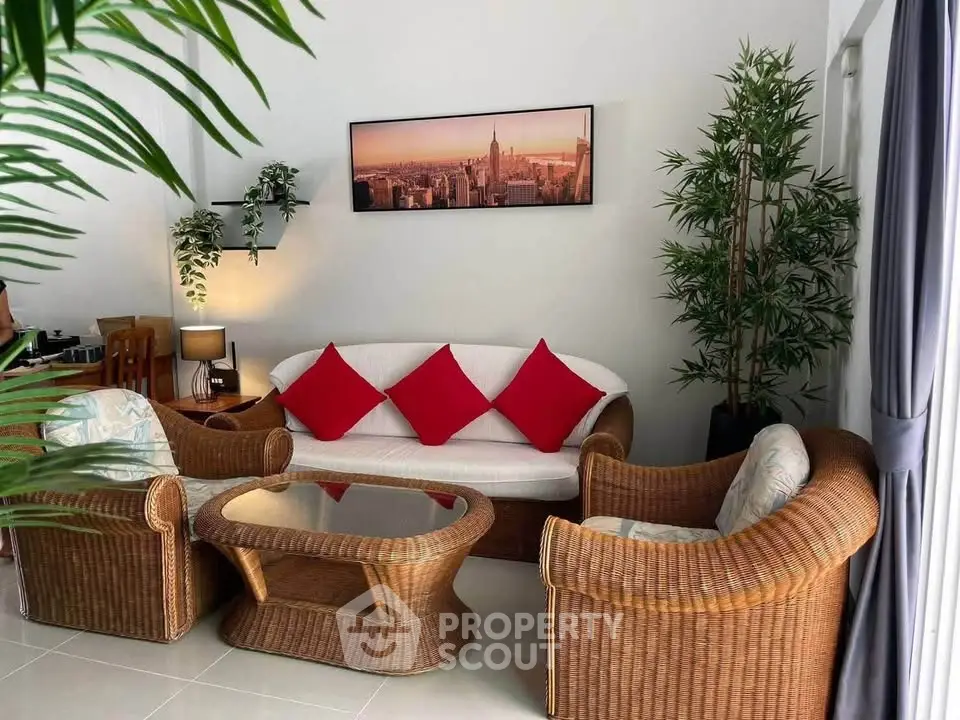 Charming living room with wicker furniture and vibrant red cushions, perfect for relaxation.
