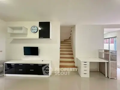 Modern living room with sleek black and white furniture and wooden staircase