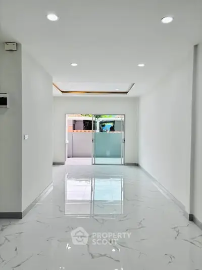 Spacious modern interior with glossy marble flooring and recessed lighting, perfect for versatile living space.