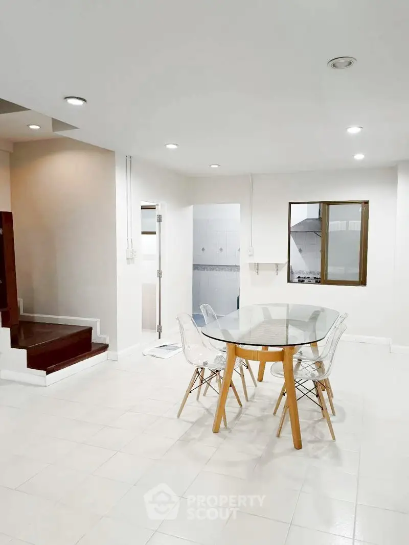 Modern dining area with glass table and transparent chairs in a bright, open space.