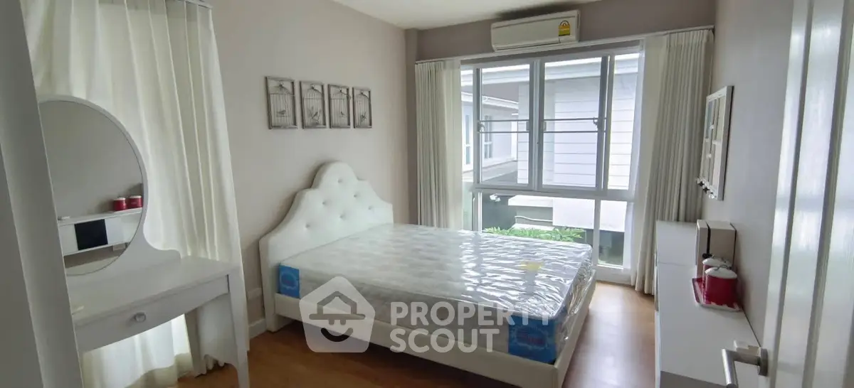 Bright and cozy bedroom with modern decor and large window view.