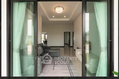 Modern living room with glass doors and elegant chandelier, showcasing spacious interior design.