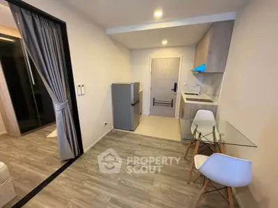 Modern studio apartment with kitchenette and stylish glass dining table.