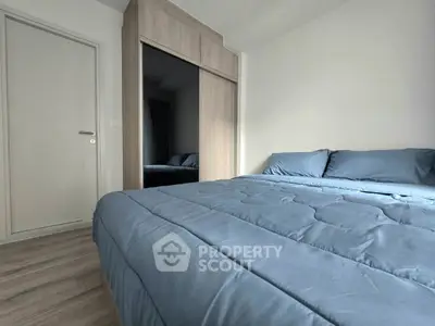 Cozy bedroom with modern wooden wardrobe and plush blue bedding, perfect for relaxation.