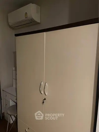 Cozy bedroom with wardrobe and air conditioning unit, perfect for comfortable living.