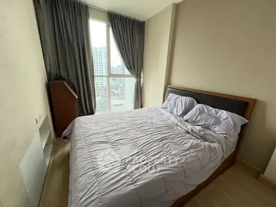 Cozy bedroom with city view, featuring a comfortable bed and large window for natural light.