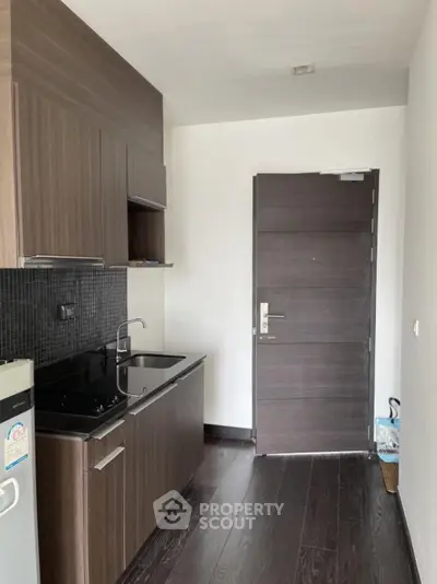 Modern compact kitchen with sleek cabinetry and dark wood flooring