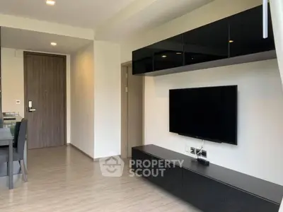 Modern living room with sleek black furniture and wall-mounted TV in a contemporary apartment.