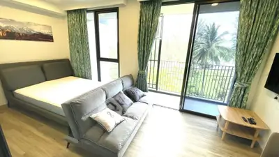 Spacious bedroom with balcony and lush garden view, featuring modern decor and ample natural light.