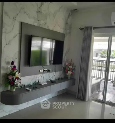 Modern living room with wall-mounted TV and sliding glass doors to balcony