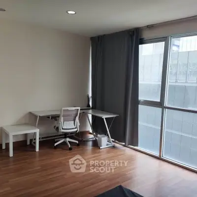 Modern study room with sleek desk and ergonomic chair, featuring large window and wooden flooring.