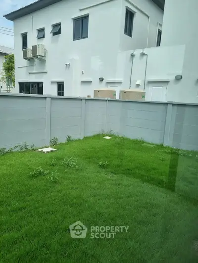 Spacious green backyard with privacy fence and modern building exterior.