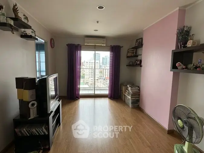 Spacious living room with gleaming hardwood floors, large windows offering city views, and a cozy pink accent wall, perfect for urban living.