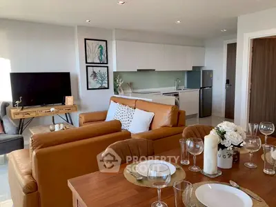 Modern open-plan living room with stylish decor and kitchen area, featuring leather sofas and dining table.