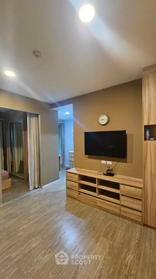Modern living room with wooden flooring and wall-mounted TV in cozy apartment.