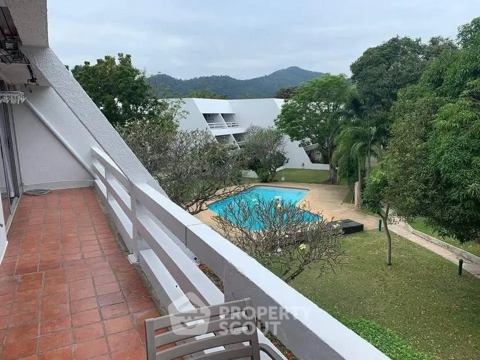 Stunning balcony view overlooking lush gardens and a serene pool, perfect for relaxation.