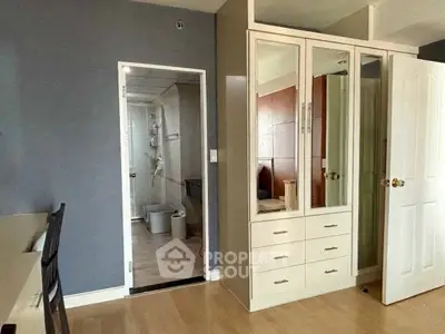Spacious bedroom with built-in wardrobe and ensuite bathroom in modern apartment.