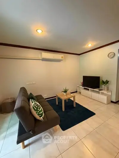 Cozy living room with modern sofa, TV, and air conditioning in a stylish apartment.