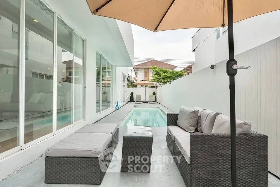 Modern outdoor patio with pool and stylish furniture in a luxurious residential setting.