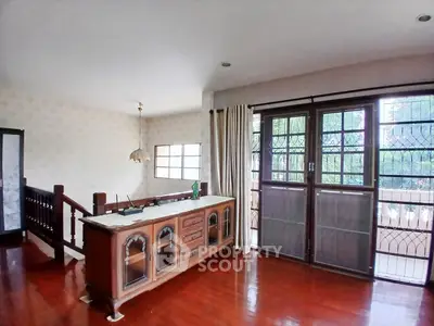 Spacious living room with wooden flooring and large windows for natural light.
