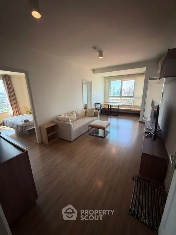 Spacious open-plan living room with modern furniture and large windows offering city views.
