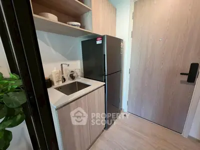Compact kitchen with modern fridge and sleek cabinetry in cozy apartment