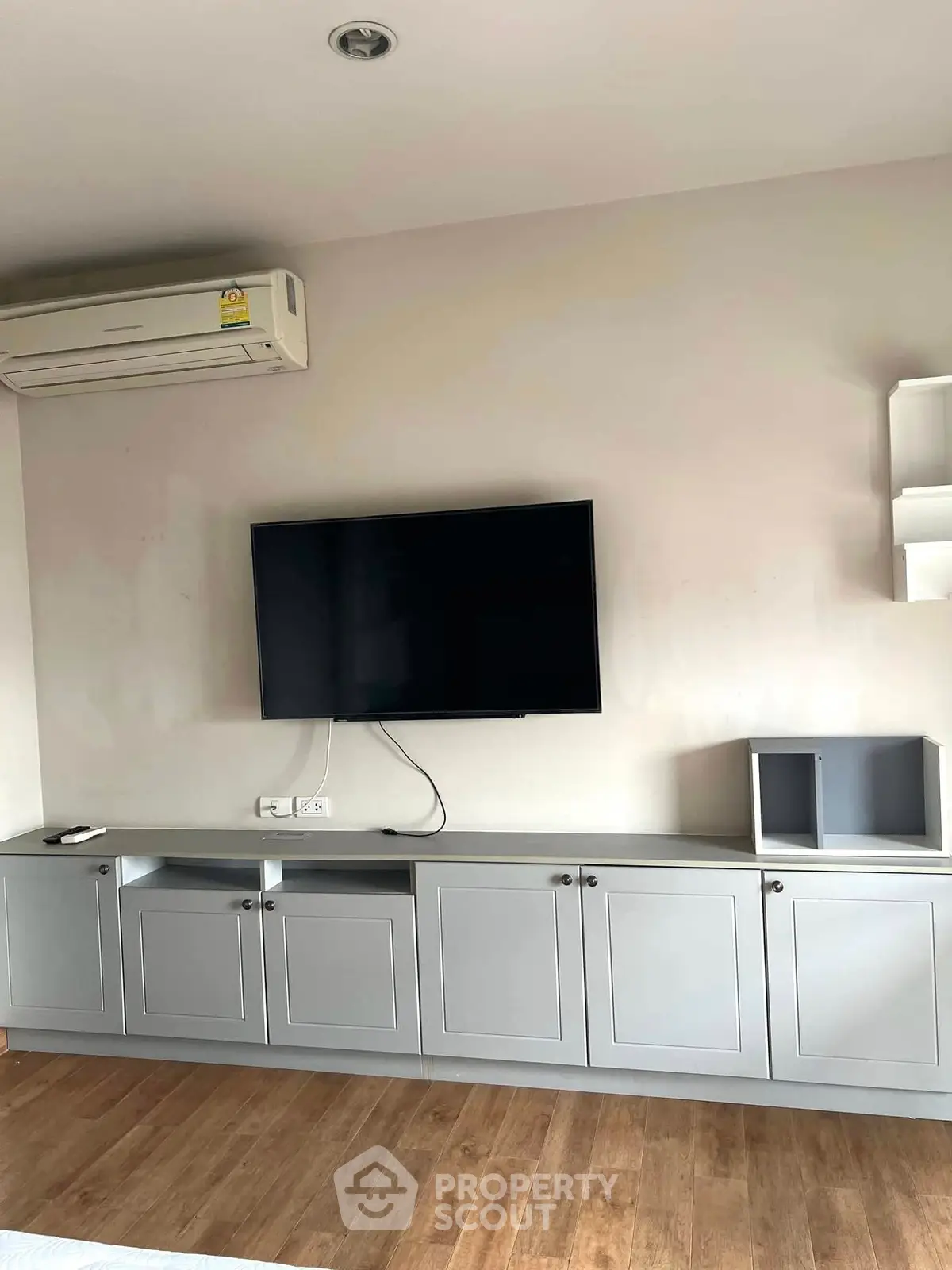 Modern living room with sleek cabinetry and wall-mounted TV, featuring stylish air conditioning unit.