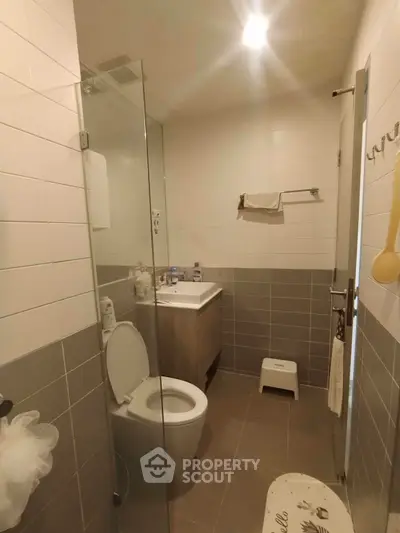 Modern bathroom with glass shower and sleek vanity in contemporary apartment.