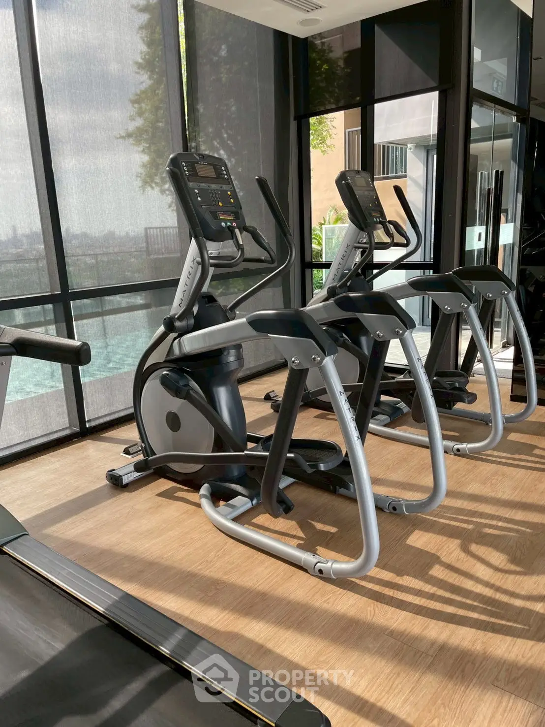 Modern gym with state-of-the-art exercise equipment and pool view in luxury residential building.