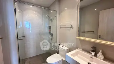 Modern bathroom with glass shower and sleek fixtures in contemporary apartment.