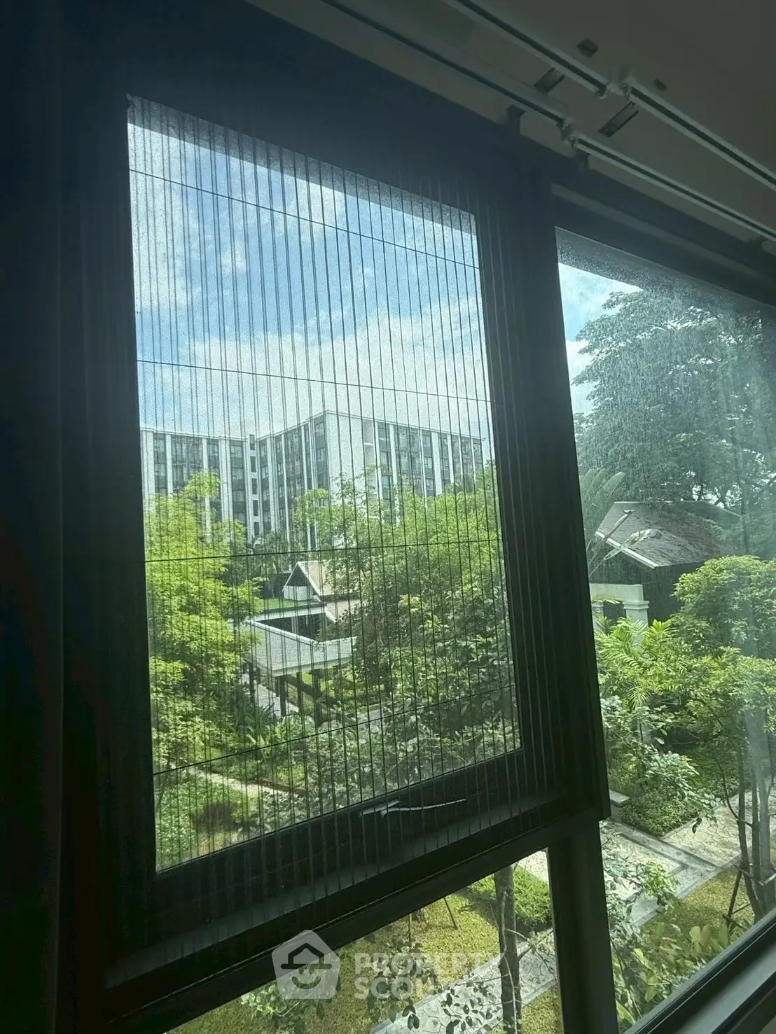 Stunning view from a modern apartment window overlooking lush greenery and urban landscape.