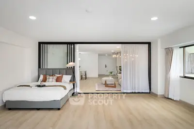 Spacious modern bedroom with open layout to living area, featuring elegant decor and natural light.