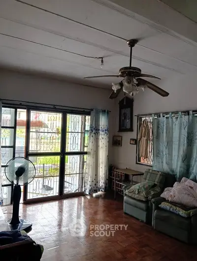 Cozy living room with ceiling fan and large windows offering natural light.