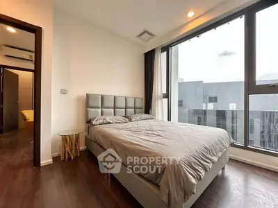 Modern bedroom with large windows and stylish decor in a high-rise apartment.